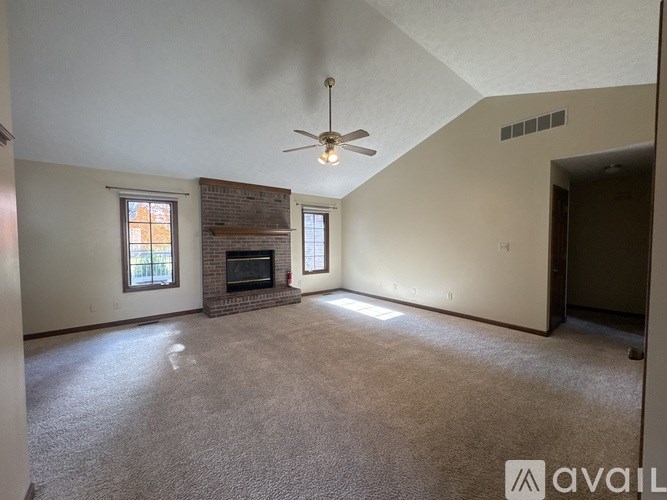 A living room with a fireplace and a ceiling fan.