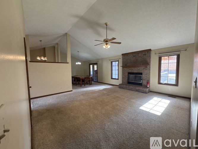 A living room with a fireplace and a ceiling fan.