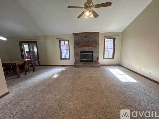 A living room with a fireplace and a ceiling fan.