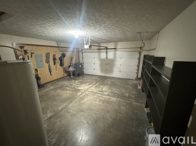 A garage with a concrete floor and a wall with various tools hanging on it.