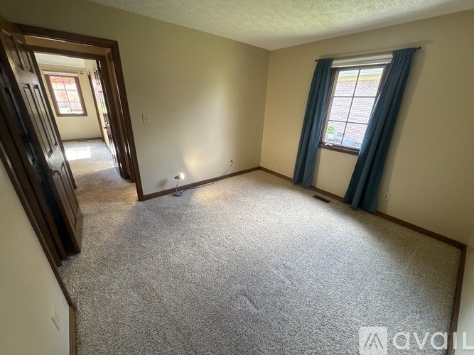 A carpeted room with a window and a door.