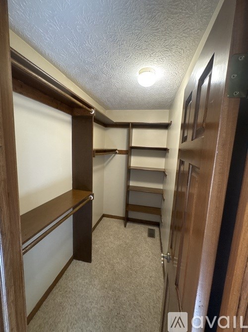 A narrow hallway with a carpeted floor and wooden walls.