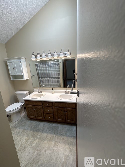 A bathroom with a toilet, sink, and mirror.