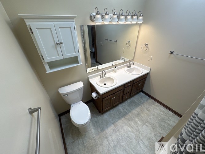 A bathroom with a toilet, sink, and mirror.