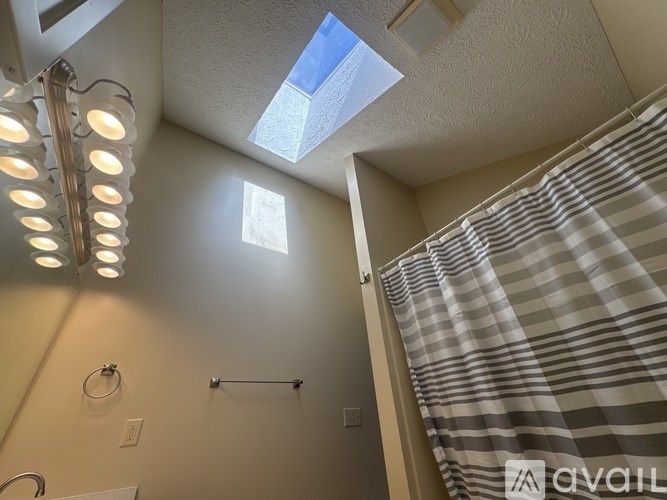A bathroom with a skylight and strip lighting.