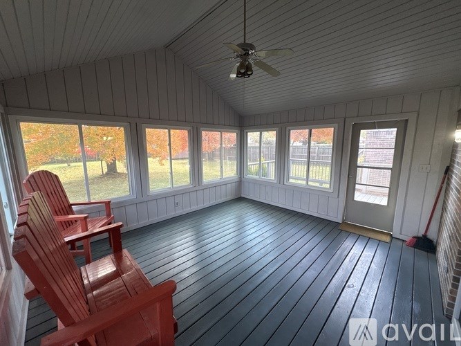 A sunroom with wooden floors and a ceiling fan.