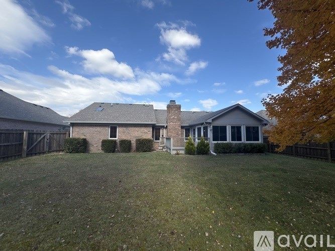 A house with a large lawn and a fence in front of it.