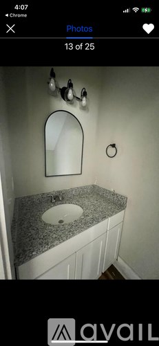 A bathroom with a granite countertop and a round mirror.