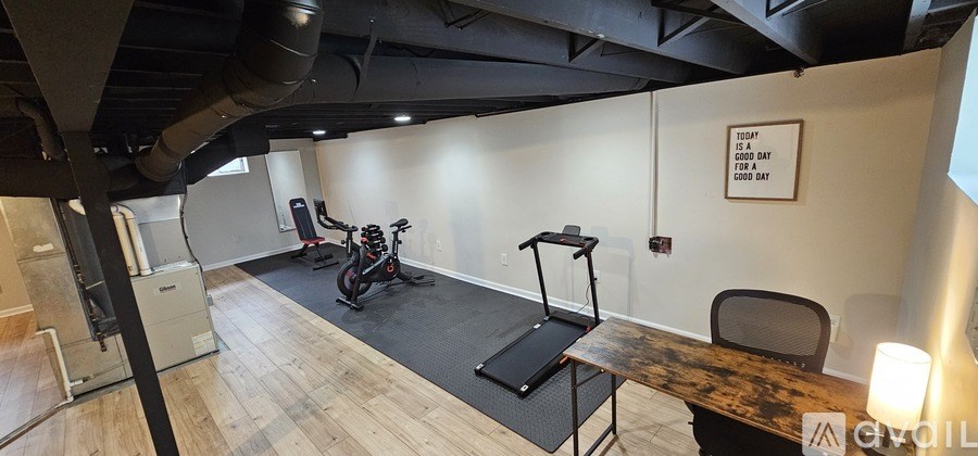 A gym with a treadmill, exercise bike, and a squat rack.