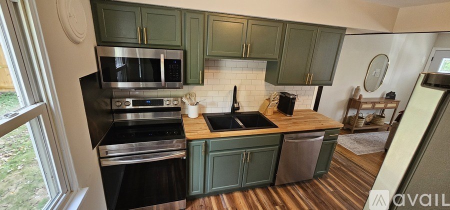 A kitchen with green cabinets and a wooden counter top.
