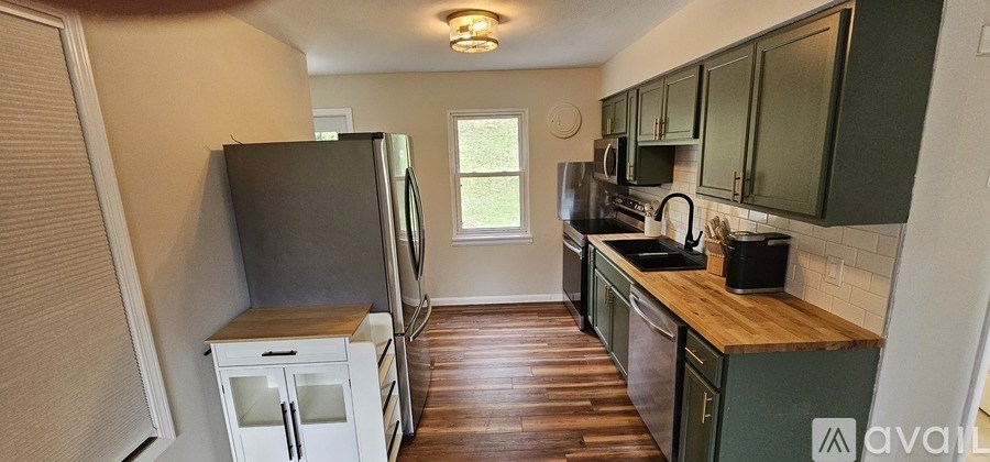 A kitchen with green cabinets and a wooden counter top.
