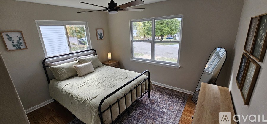 A bedroom with a bed, a fan, and a window.