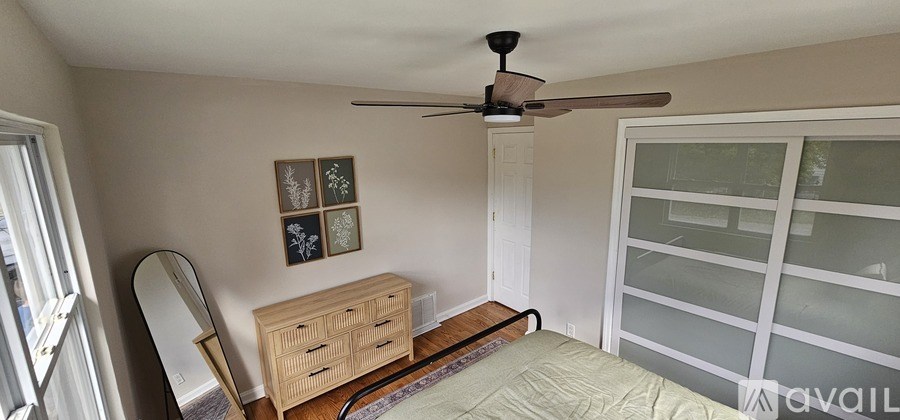 A room with a bed, a dresser, a mirror and a ceiling fan.