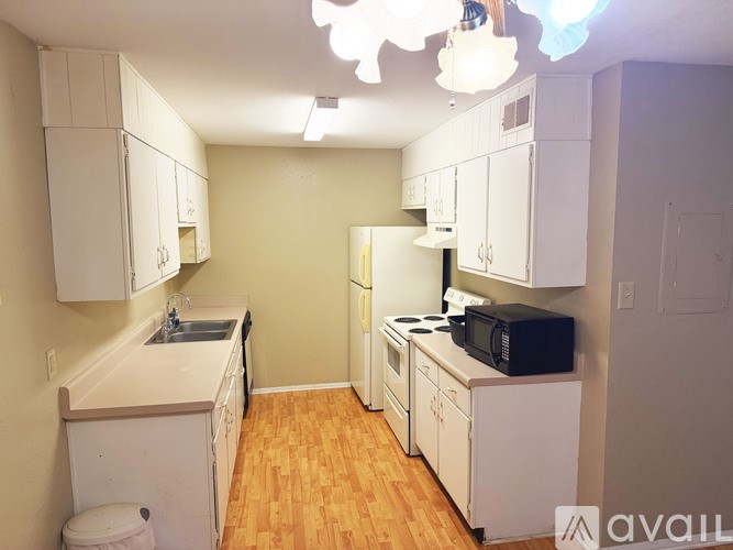 A kitchen with white cabinets and a wooden floor.