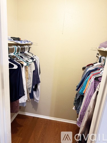 Clothes hanging on a rack in a closet.