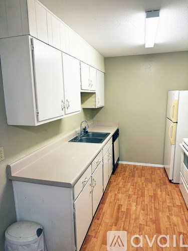 A kitchen with white cabinets and a wooden floor.