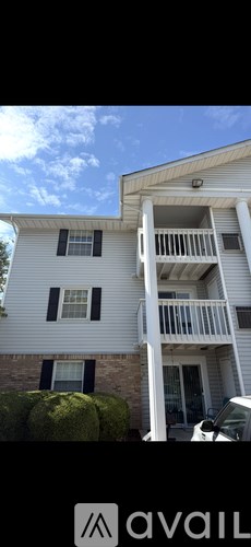 A white house with a balcony and a car parked in front.
