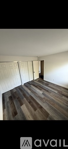 A room with wooden flooring and white walls.