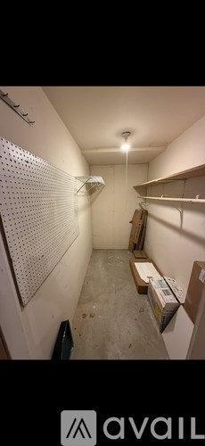 A long hallway with a white wall and a pegboard on the wall.