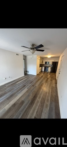 A room with a ceiling fan and wooden flooring.
