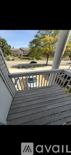 A wooden staircase leading to a balcony with a view of a tree and a house.