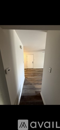 A hallway with a wooden floor and white walls.