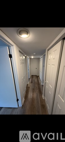 A long hallway with white doors and wooden floors.