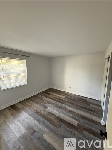 A room with wooden flooring and a window with blinds.