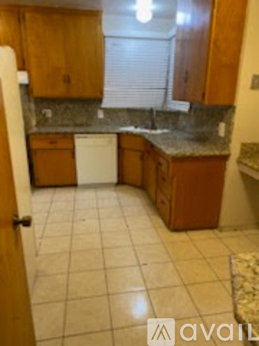 A kitchen with brown cabinets and a white dishwasher.
