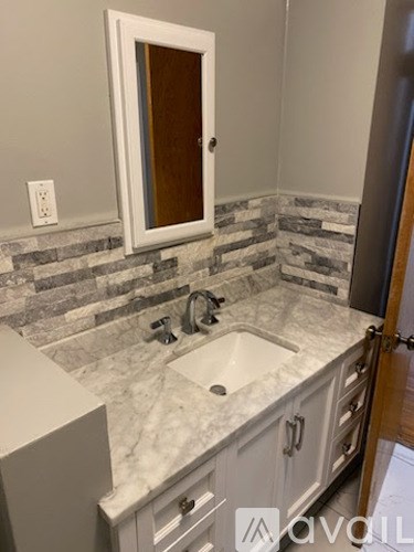 A bathroom with a marble countertop and a mirror above the sink.