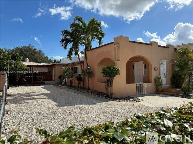 A house with a driveway and a palm tree in front.