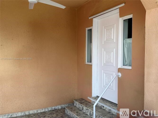 A white door with a window and a fan above it.