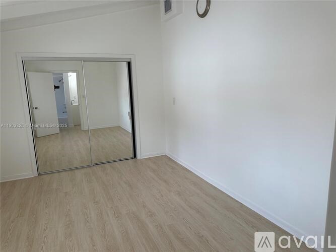 A room with a mirror and wooden flooring.