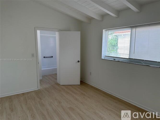 A room with a door and a window with blinds.