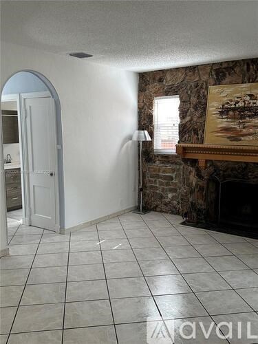 A room with a stone fireplace and a painting above it.