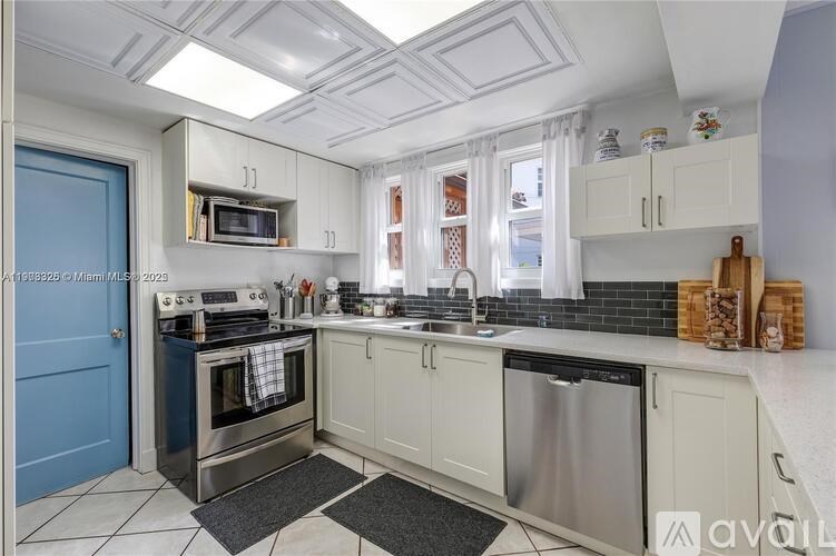 A kitchen with a blue door and white cabinets.