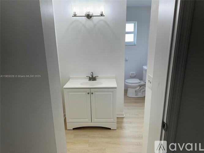A white bathroom with a sink and a toilet in the background.