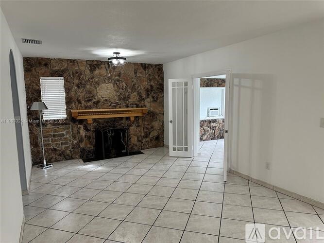 A room with a stone fireplace and a tiled floor.