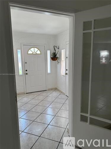 A hallway with a white door and tiled floor.