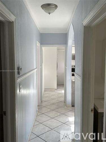 A long hallway with white doors and tiled floors.