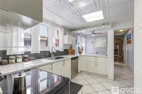A kitchen with a stainless steel sink and a black countertop.