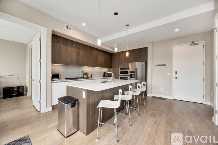 A modern kitchen with a bar area and white chairs.