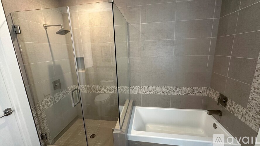 A modern bathroom with a glass shower stall and a white bathtub.