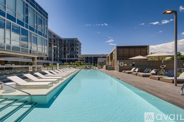 A large outdoor swimming pool with sun loungers and a modern building in the background.