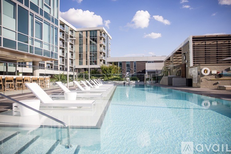 A pool with sun loungers and a building in the background.
