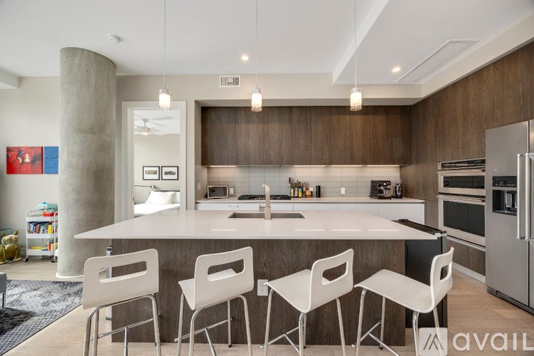 A modern kitchen with a large island and white chairs.