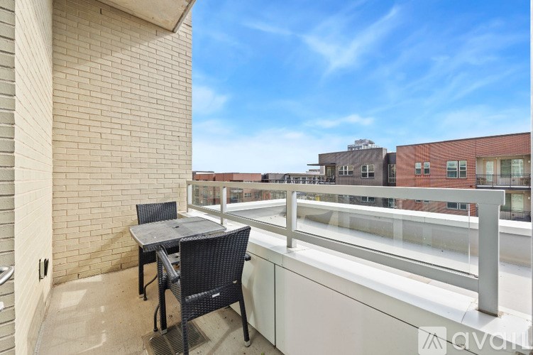 A balcony with a table and chairs overlooking a cityscape.