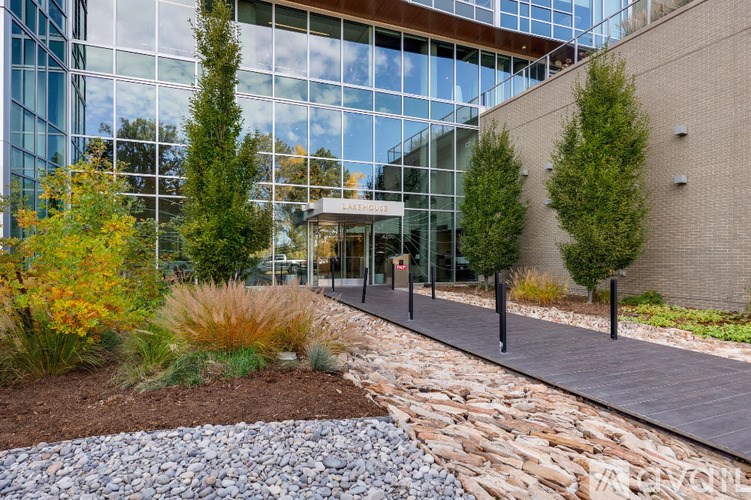 A modern building with a glass facade and a stone pathway leading to the entrance.