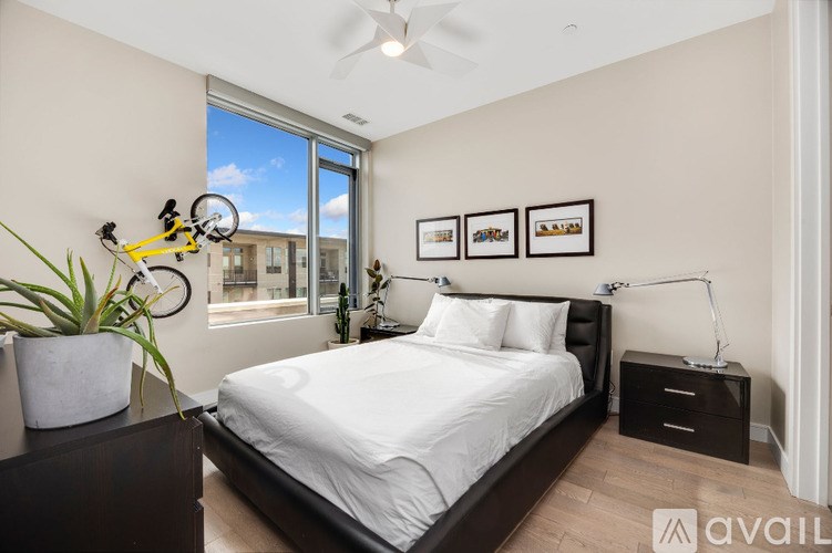 A bedroom with a large bed, a bicycle on the wall, and a plant on the nightstand.