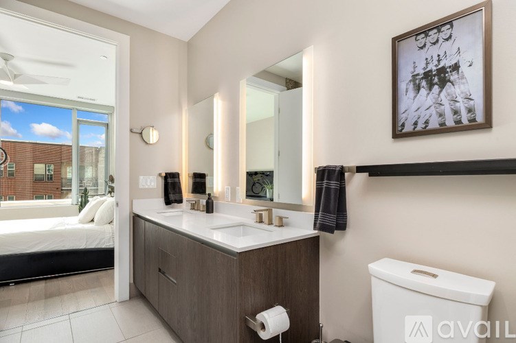 A bathroom with a large mirror, a white sink, and a toilet.